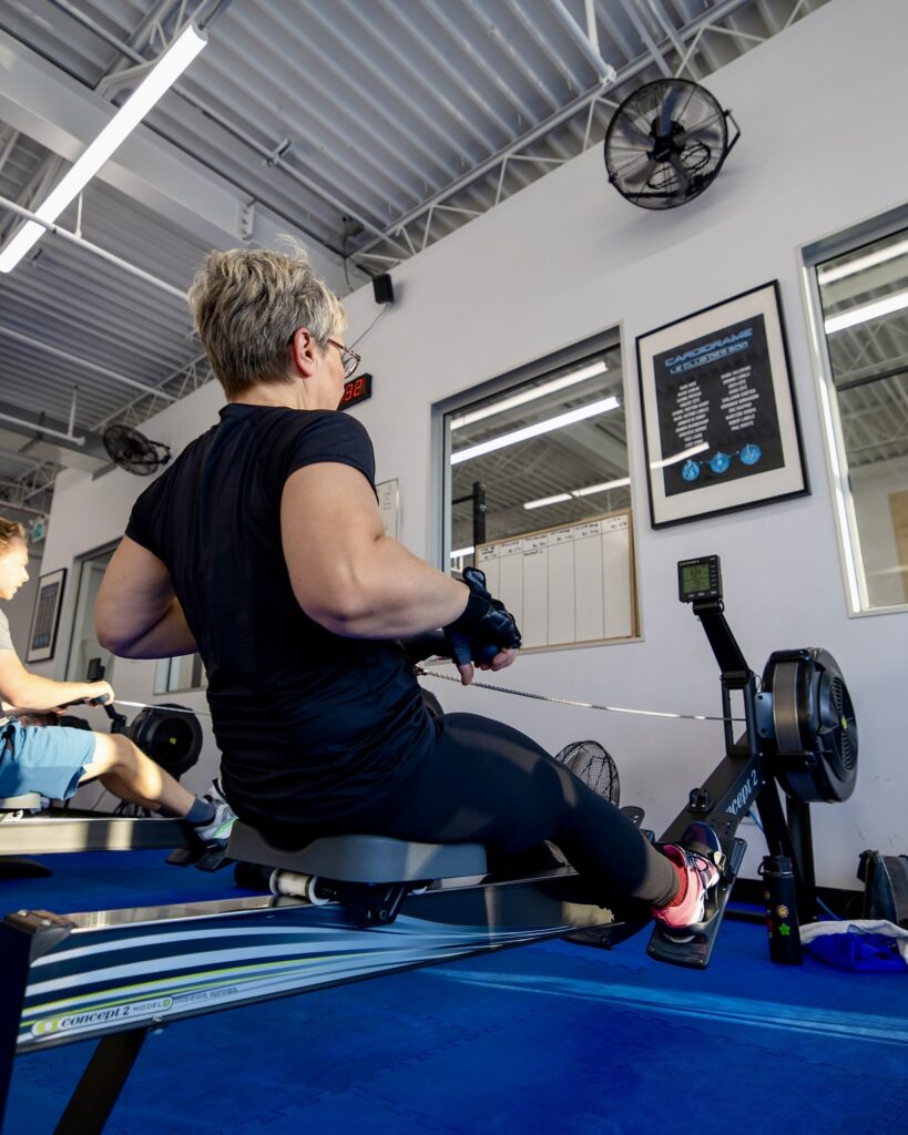 Patiente s'entraînant sur un rameur afin de maintenir sa capacité cardiovasculaire dans le cadre d'un programme de préparation avant une chirurgie du genou